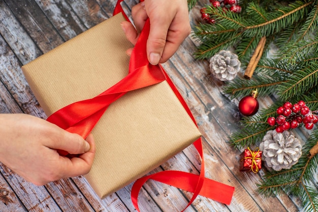 Kerstcadeau meisje wikkelt een cadeau met een rood lint close-up