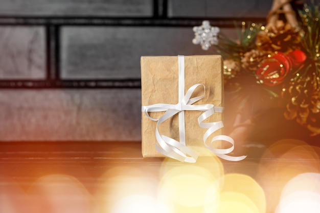 Kerstcadeau met wit lint en grenen decor op donkere bakstenen achtergrond. kerst geschenkdoos. nieuwjaar huidige doos.