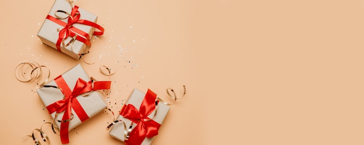 Foto kerstcadeau of huidige doos met een rood lint boog en gouden versieringen op pastel achtergrond.