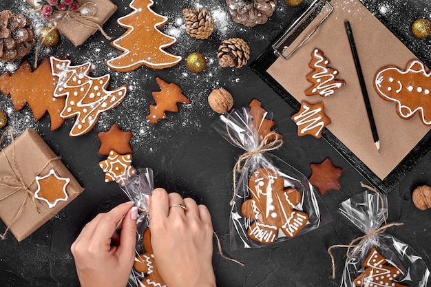 Kerstcadeau peperkoek op donkere achtergrond koekjes in feestelijke verpakking vrouw verpakt chris...