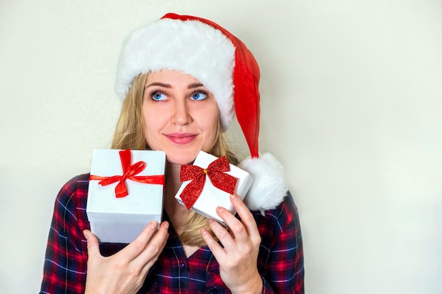 Kerstcadeau's. Jonge blanke vrouw in kerstmuts met geschenken in haar handen op een wit