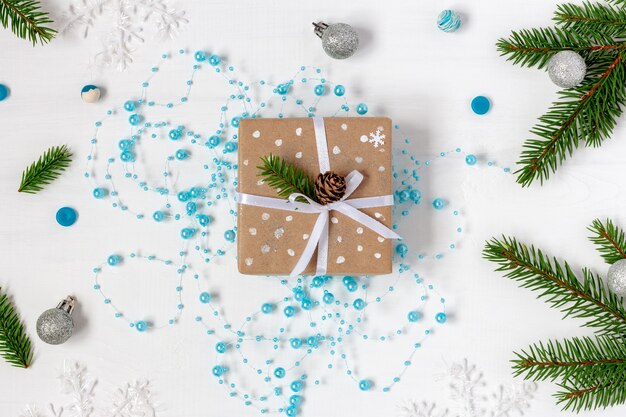 Kerstcadeau verpakt in eco-papier op de blauwe slinger naast vuren twijgen
