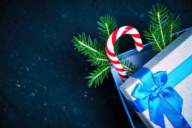 Kerstcadeaudoos gebonden met blauw lint met strik met groene kerstboom en karamel op donkere achtergrond