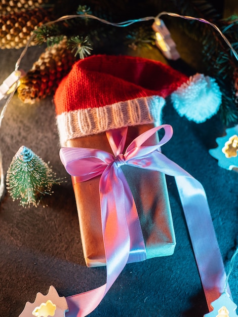 Foto kerstcadeaudoos in de rode hoed van de kerstman. gewikkeld in papier en vastgebonden met paars lint bovenaanzicht