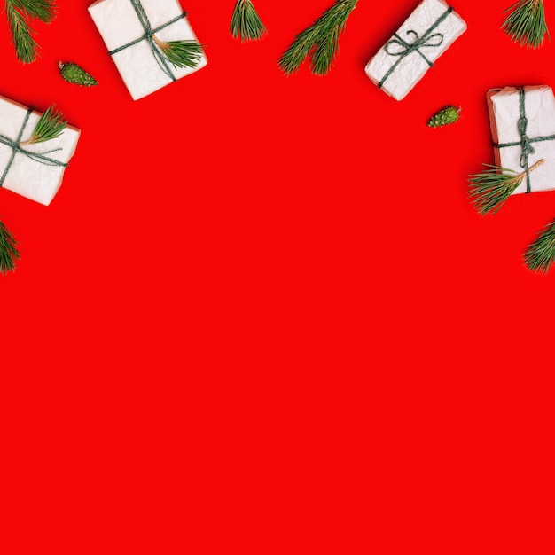 Kerstcadeaudozen of cadeautjes versierde natuurlijke dennentakken en groene dennenappels op rood