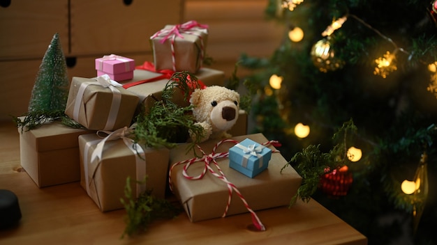 Kerstcadeaudozen op houten tafel in de buurt van de kerstboom in de woonkamer.