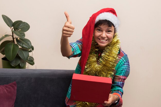 Kerstcadeaus concept: gelukkige jonge vrouw met kerstmuts met open geschenkdoos
