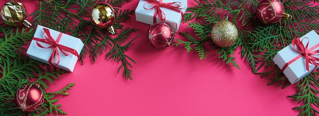 Kerstcadeaus en feestelijk decor op een roze achtergrond. Bannerformaat.