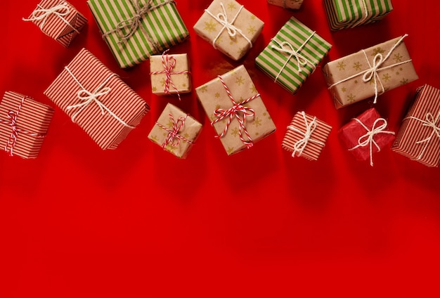 Kerstcadeaus Giften op een rode achtergrond. Eenvoudige, klassieke rood en wit verpakte geschenkdozen met strikken en kerstversieringen