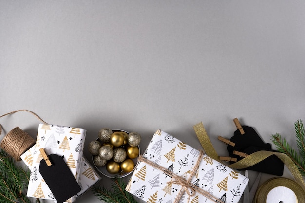 Kerstcadeaus in wit inpakpapier met een sierlijk sparrentakje zwarte tags gouden ballen