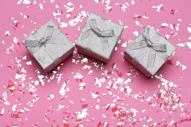 Kerstcadeaus met roze lint op roze pastelachtergrond met feestelijke decoraties