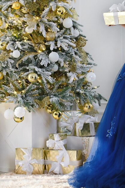 Kerstcadeaus onder een versierde kerstboomachtergrond Onderdeel van elegante blauwe jurk