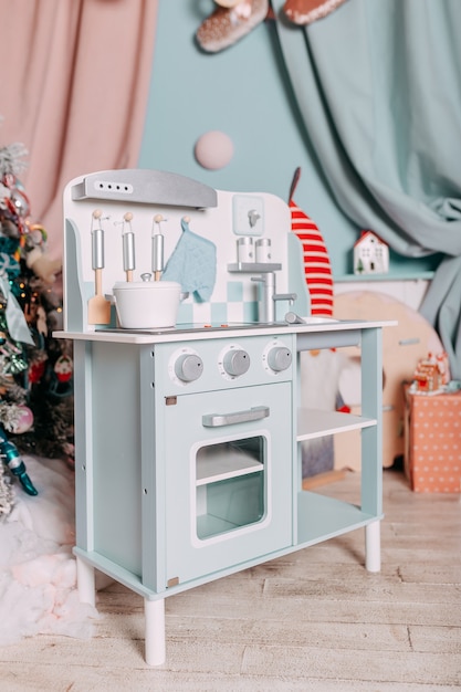 Kerstcadeaus voor kinderen onder de boom. Speelgoedkeuken aanwezig voor meisjes. Kerstcadeau onder de boom. Speelgoed houten keuken en gerechten.