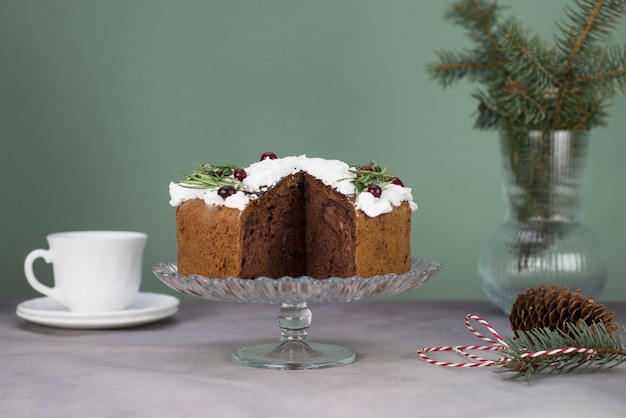 Kerstcake met rozemarijn en rode bessen op een standaard op een grijze en groene achtergrond