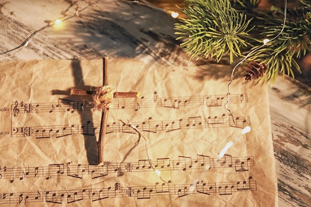 Kerstcompositie met houten kruis en muziekblad op tafel
