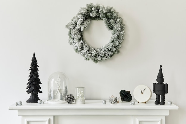 Kerstcompositie op de witte schoorsteen in het interieur van de woonkamer met prachtige decoratie. Kerstboom en krans, kaarsen, sterren, licht. Ruimte kopiëren. Sjabloon.