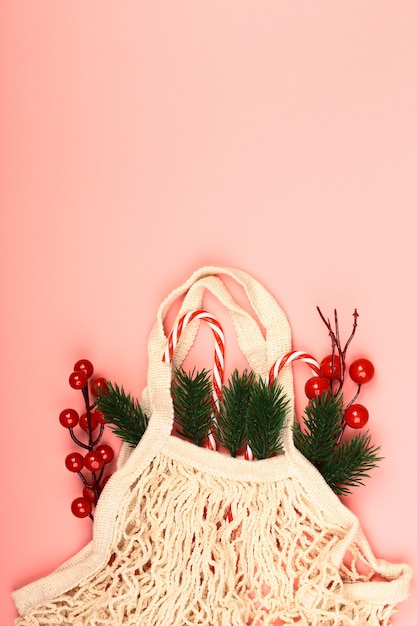 Kerstcompositie op een roze achtergrond. Zero waste. Milieuvriendelijke herbruikbare tas met nieuwjaarsgeschenken. Creatief concept. Vlakke stijl, bovenaanzicht.