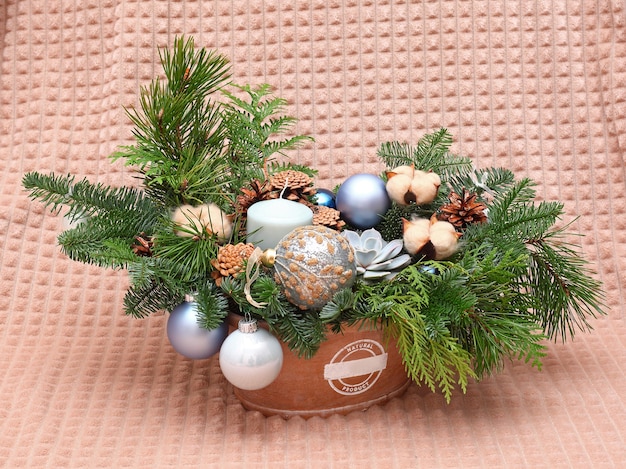 Kerstcompositie van dennentakken, kegels, katoen, ballen en kaars. Close-up shot. Op beige achtergrond