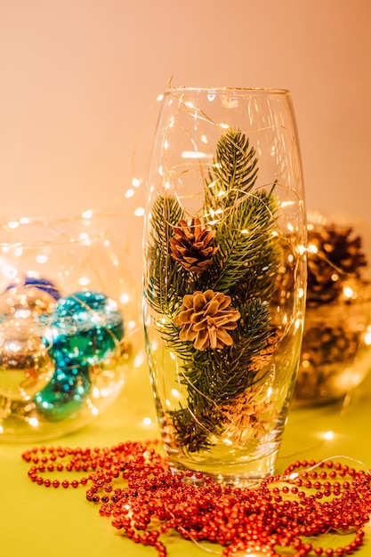 Kerstcompositie van een glazen vaas met dennentakjes en kegels
