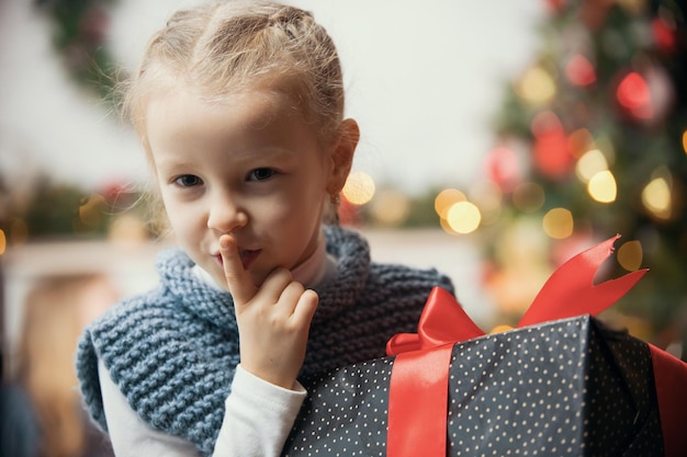 Kerstconcept een klein meisje drukt een vinger op haar lippen