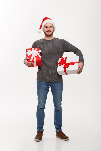 Kerstconcept Gelukkige jonge man met baard draagt veel cadeautjes geïsoleerd op een witte achtergrond