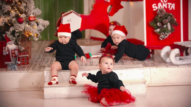 Kerstconcept kleine baby's die op het tapijt zitten en spelen met een lege doos