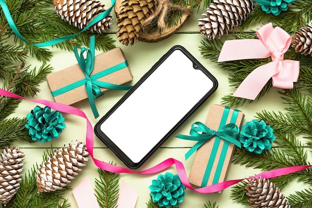 Kerstconcept met dennentakken met de telefoon naar uw reclame.