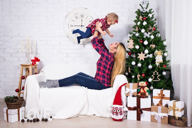 Kerstconcept - moeder en haar dochtertje met kerstboom in de woonkamer