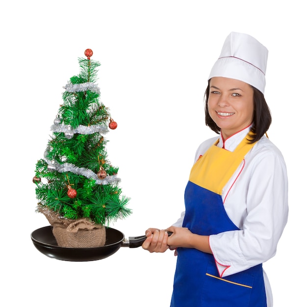 Kerstconcept. Mooie jonge vrouw chef-kok met versierde kerstboom in koekenpan op een witte achtergrond