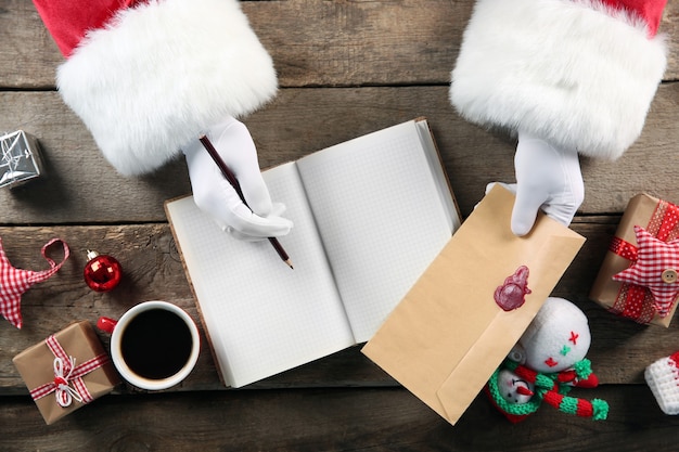 Kerstconcept. Santa Claus-handen schrijven in notitieboekje op houten oppervlak
