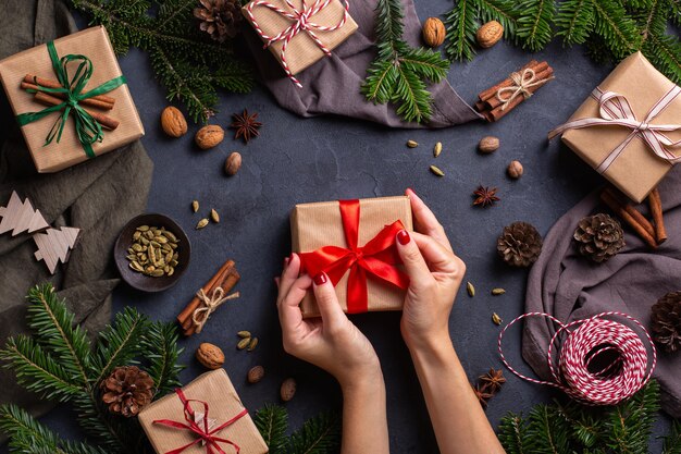 Kerstconcept vrouwelijke handen die handgemaakte milieuvriendelijke geschenkdozen inpakken