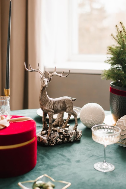 Kerstdecor van een feestelijke tafel met een beeldje van een hert en een glas