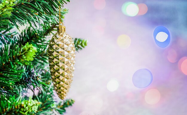 Kerstdecoratie dennenappel op een tak van een boom op een onscherpe gekleurde achtergrond met bokeh