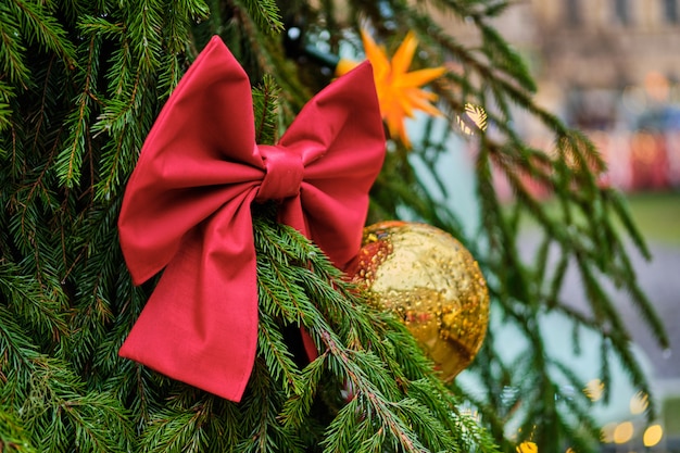 Kerstdecoratie in de vorm van een rode strik met een gele bal op een groene kerstboom