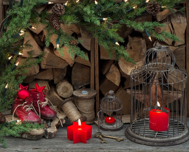 Kerstdecoratie in retrostijl met rode brandende kaarsen, vintage babyschoentjes en kerstboomtakken