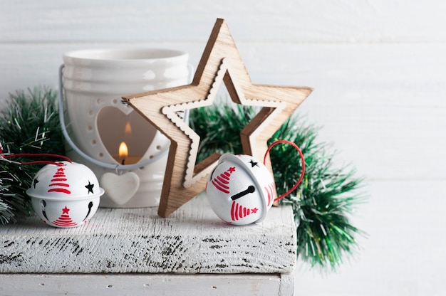 Kerstdecoratie met rode en witte jingle bells en kaars op witte rustieke tafel