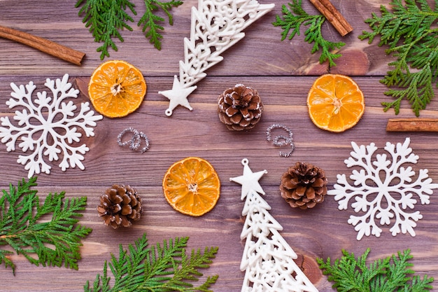 Kerstdecoratie met thujatakken, sneeuwvlokken, dennenappels, kaneel en mandarijn