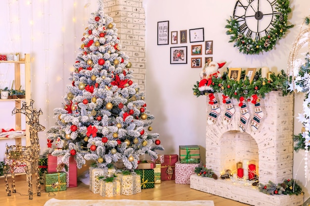 Kerstdecoratie van de woonkamer de decoratie van de kamer Kerst met sneeuw bedekte dennenboom met speelgoed geschenkdozen onder de boom gezellige open haard in de kamer