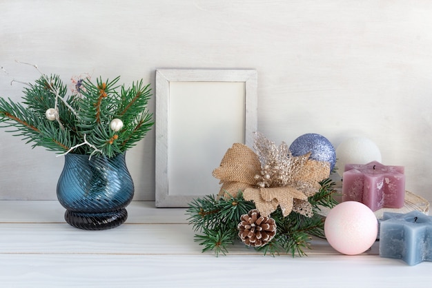 Kerstdecoratie wit frame mockup met een boeket van sparren en kerstballen op een witte tafel