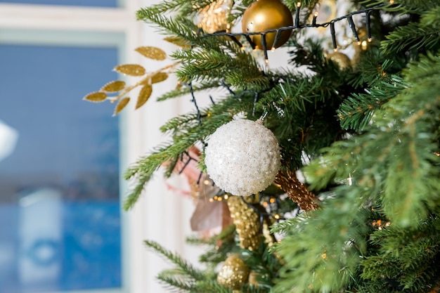 Kerstdecoratie witte en gouden ballen die aan pijnboomtakken hangen, kerstboomslinger en orna