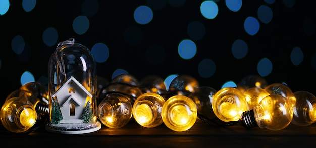 Kerstdecoratie Witte huis in glas tussen lampen lamp, blauwe bokeh donkere achtergrond