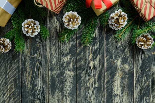 Kerstdecoraties, geschenkdoos en dennenappels op een grijze houten tafel. Bovenaanzicht, kopie ruimte.