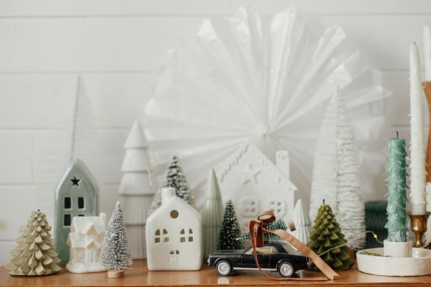 Kerstdorpje decoratie in feestelijke scandinavische kamer Moderne miniatuur kerstbomen stijlvolle huizen en auto dragende boomscène Atmosferische wintervakantie decor