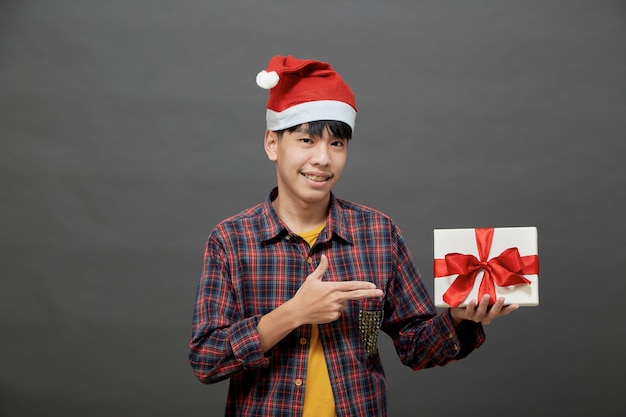 Kerstfeest en vakantie concept. jonge Aziatische man met geschenkdoos studio-opname, geïsoleerd op een grijze achtergrond