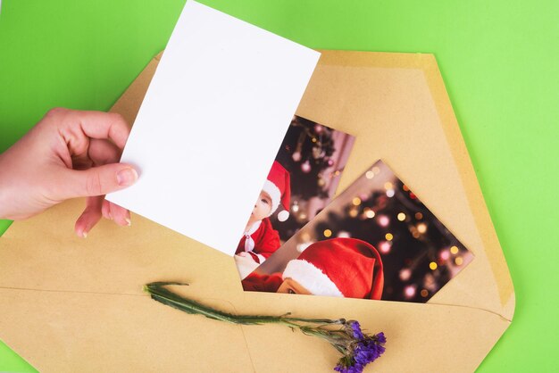 Kerstfoto's van een baby in de postenvelop en blanco foto in de hand op een groene achtergrond.