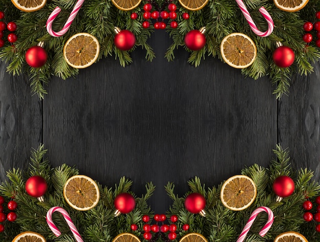 Foto kerstframe met sparren takken en rode kralen op de zwarte houten achtergrond kopieer ruimte