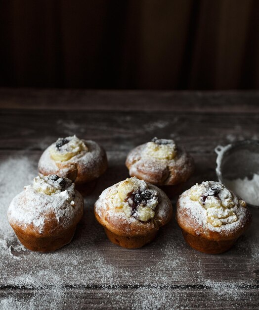 Kerstgebakjes op een houten tafel Cupcakes met bessen en room bestrooid met poedersuiker