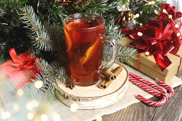 Kerstglas warme glühwein met sinaasappels kruidnagel kaneel en anijs in de buurt van geschenken en decor