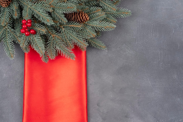 Kerstgrenstakken van dennenboom met decoratie en rode winterbessen, rode zijde en krans