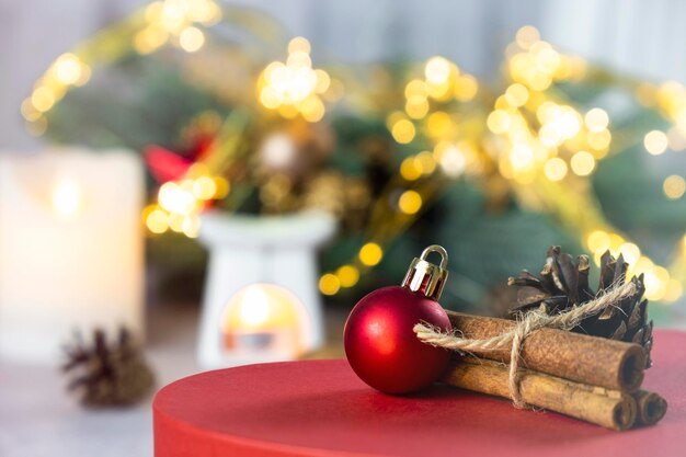 Foto kerstgroetkaart met rode bal kaneel stokjes en sparren kegel kaarsen sparren tak kerstversieringen en warme bokeh lichten vrolijk kerstfeest en gelukkig nieuwjaar wonder stemming sfeer